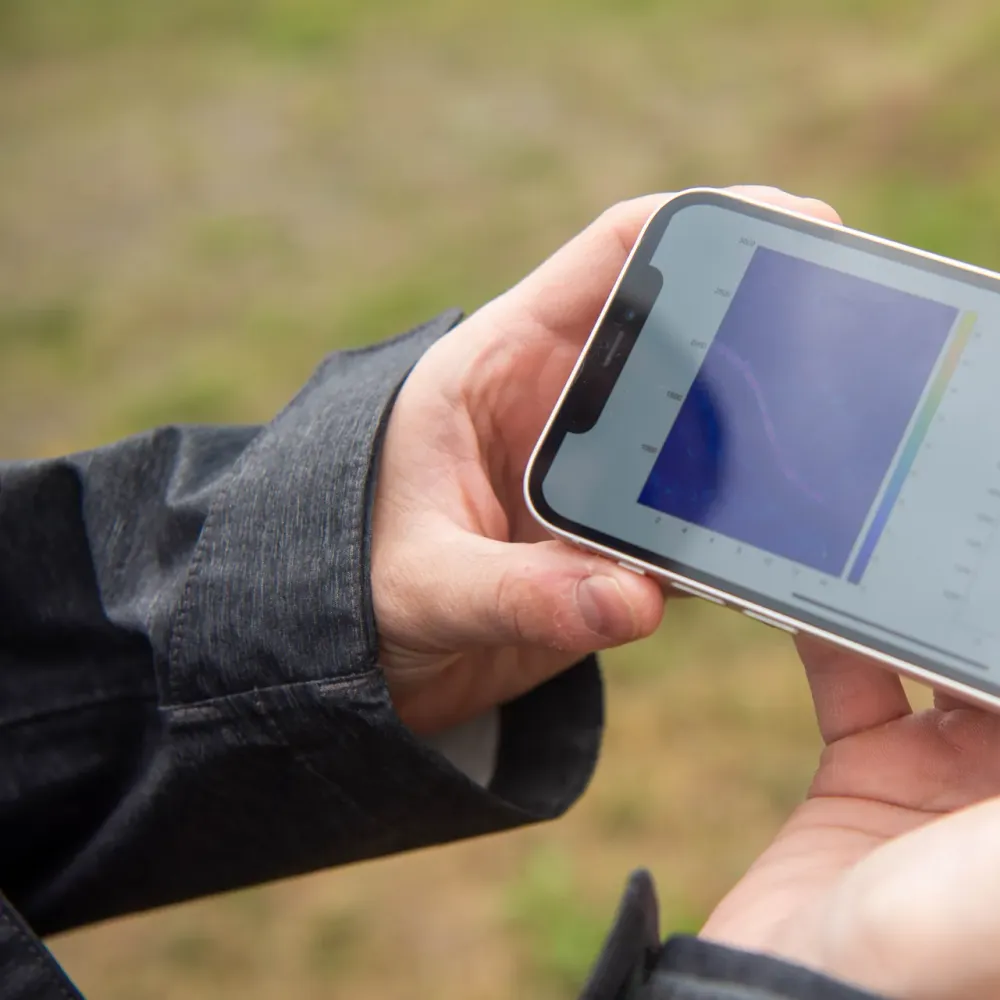 Two hands holding a smartphone sideways outdoors